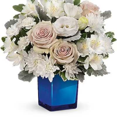 White and blush flower arrangement in a blue glass vase