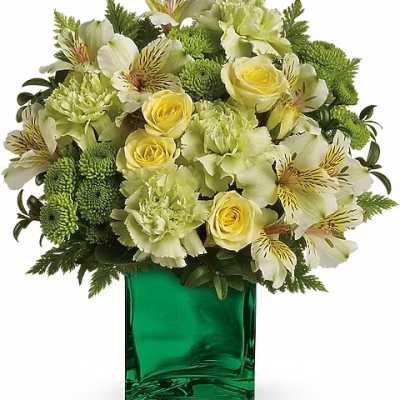 Green and yellow floral arrangement in a square glass vase