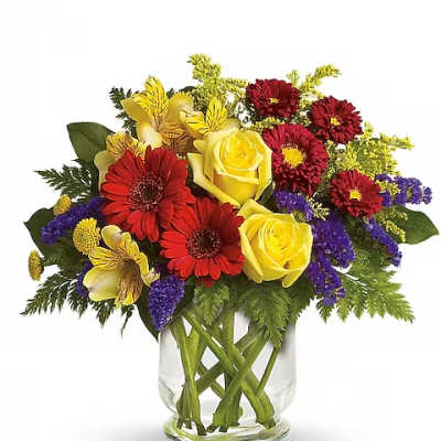 Mixed bouquet of yellow roses, red daisies, and purple flowers in a glass vase