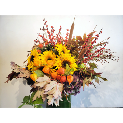 Autumn arrangement with sunflowers, berries, and fall leaves in a vase
