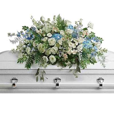White and blue floral casket spray on a white casket