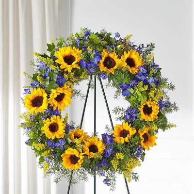 Sunflower wreath with blue flowers on a black stand