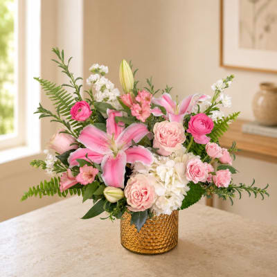 Pink lilies and roses arranged in a gold vase