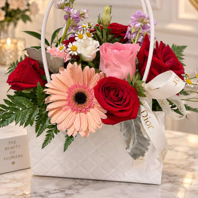 Mixed bouquet of red and pink roses in a white gift bag