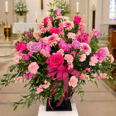 Large pink and lavender floral arrangement in a church setting