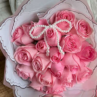 Bouquet of pink roses wrapped in decorative paper with a pearl bow