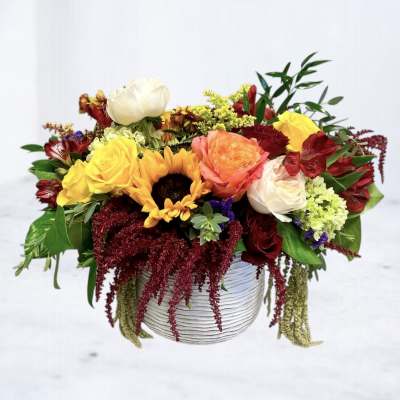 Mixed bouquet in a white ribbed vase with sunflowers and roses