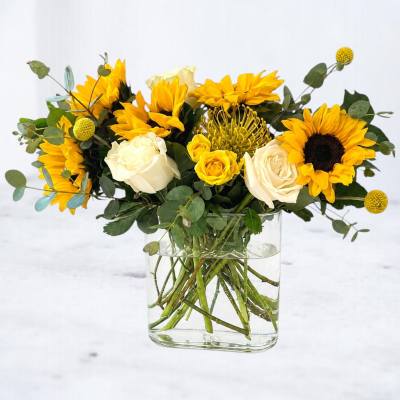 Yellow sunflowers and white roses arranged in a clear glass vase