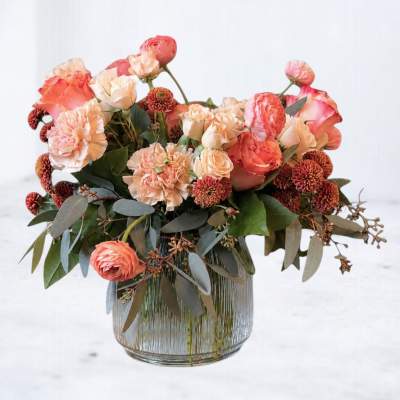 Peach and coral flower arrangement in a clear glass vase