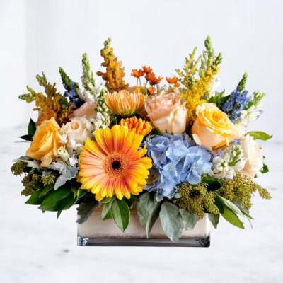 Mixed bouquet in a rectangular glass vase with roses, gerbera daisies, hydrangea, and snapdragons