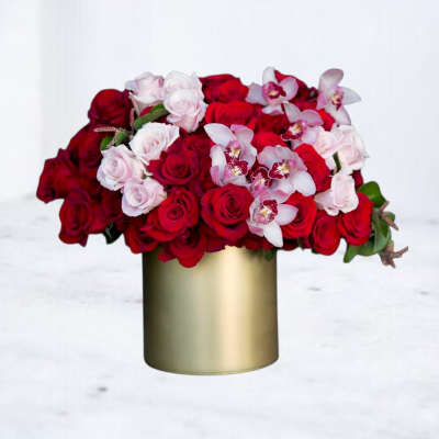 Red and pale pink roses with white orchids in a gold vase