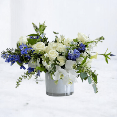 White and blue floral arrangement in a clear glass vase