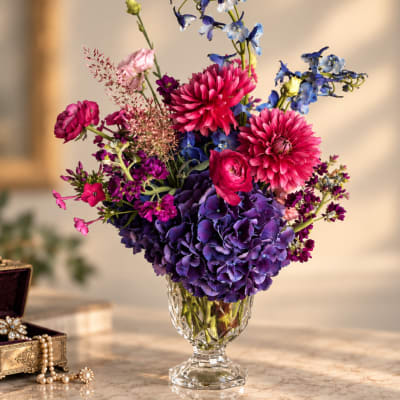 Colorful bouquet of pink, purple, and blue flowers in a clear glass vase