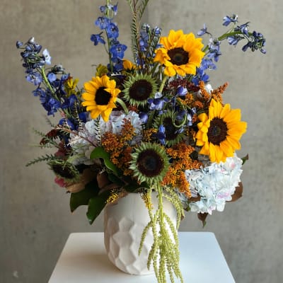 Sunflower arrangement with blue flowers in a white textured vase
