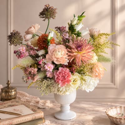 Mixed pastel flower arrangement in a white pedestal vase