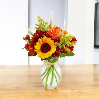 Sunflower and orange rose arrangement in a clear glass vase