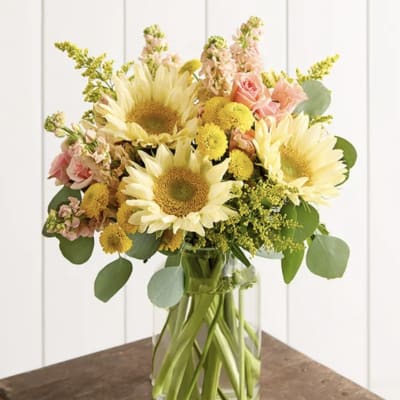 Sunflower bouquet with pink roses and yellow button flowers in a glass vase