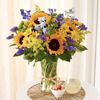 Sunflower bouquet in a glass vase with purple and blue accent flowers