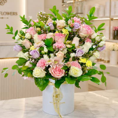 Mixed pink, white, and lavender roses in a white hatbox
