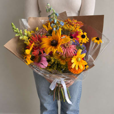 Colorful mixed bouquet with sunflowers and daisies wrapped in brown paper