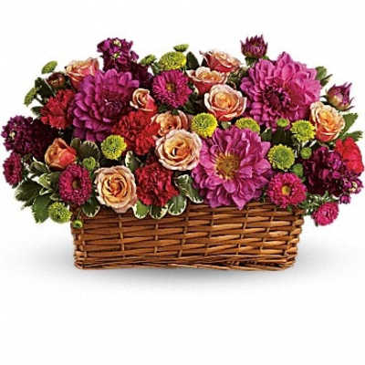 Mixed pink and peach flowers arranged in a wicker basket