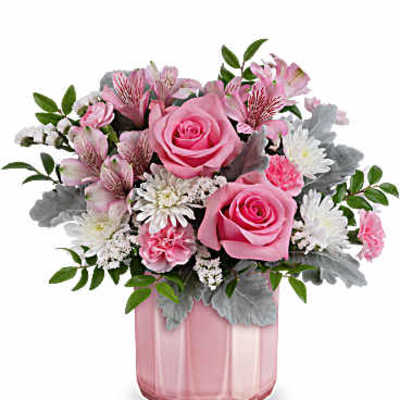 Pink roses and mixed blooms arranged in a pink glass vase