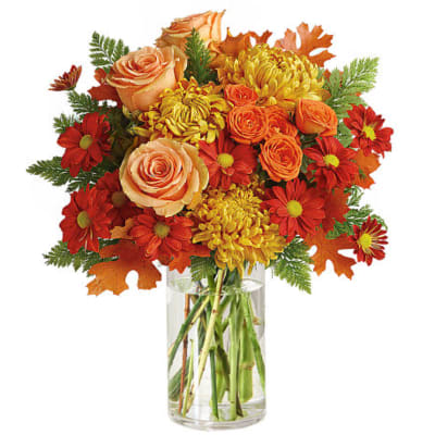 Autumn bouquet of roses and daisies in a clear glass vase