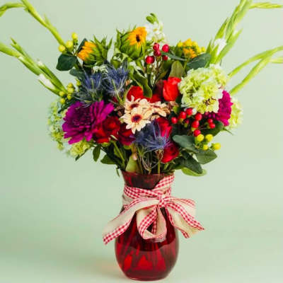 Colorful mixed bouquet in a red glass vase with a gingham ribbon