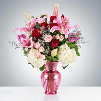 Pink and red mixed flower arrangement in a pink glass vase