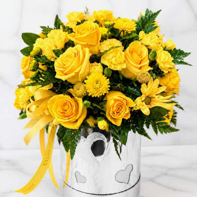 Yellow roses and mums in a silver heart-decorated vase with yellow ribbon
