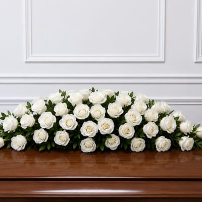 White rose casket spray with green foliage