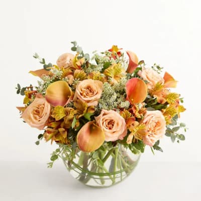 Peach roses and orange calla lilies in a clear glass vase