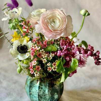 Mixed bouquet in a turquoise glass vase with pale pink and white blooms