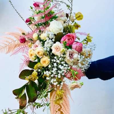 Handheld bouquet of pink and cream roses with airy filler flowers