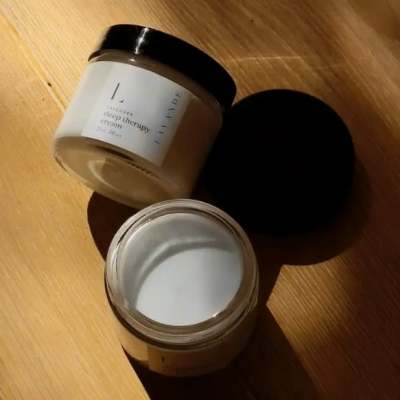 Two cosmetic cream jars with black lids on a wooden surface