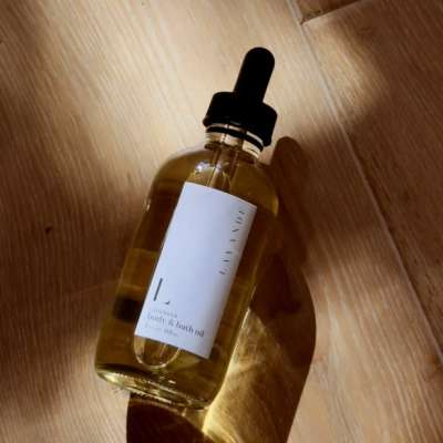 Amber dropper bottle of body and bath oil on a wooden surface
