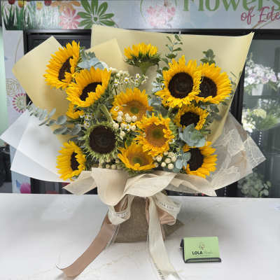 Bouquet of sunflowers wrapped in cream paper with a ribbon bow