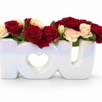 Red and cream roses arranged in a ceramic "love" vase