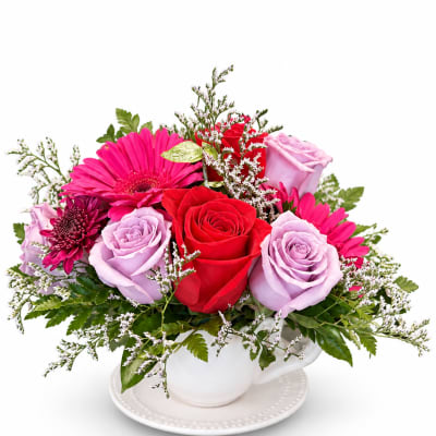 Mixed bouquet of roses and gerbera daisies in a white teacup vase