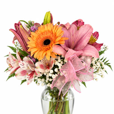 Mixed bouquet of pink lilies and orange gerbera daisies in a glass vase