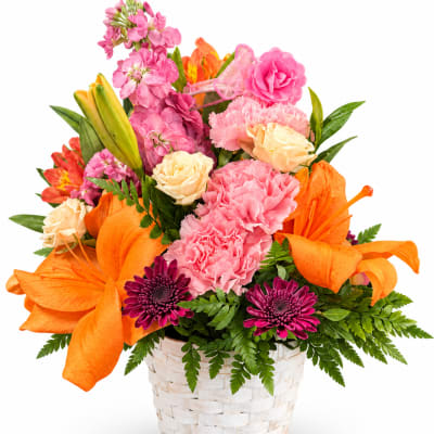 Bright mixed bouquet in a white woven basket with pink, orange, and cream flowers