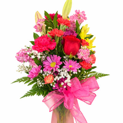 Colorful mixed bouquet in a pink vase with a large pink ribbon