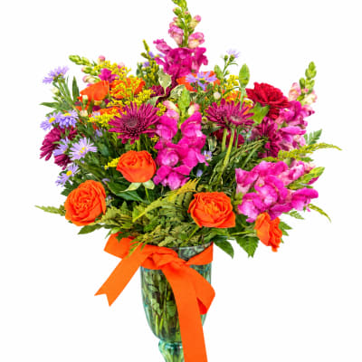 Colorful mixed bouquet in a green glass vase with an orange ribbon
