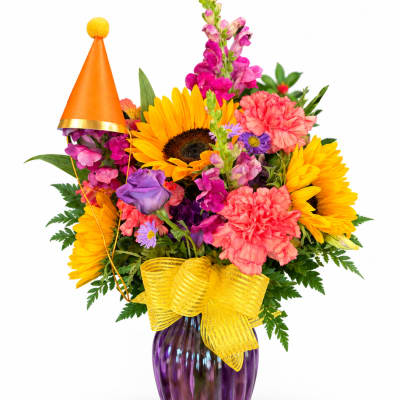 Colorful bouquet with sunflowers, pink carnations, and snapdragons in a purple vase