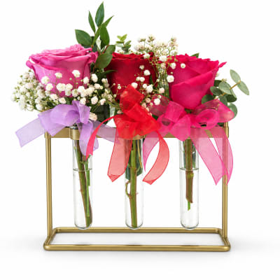 Three rose arrangements in glass tubes on a gold stand with ribbon bows