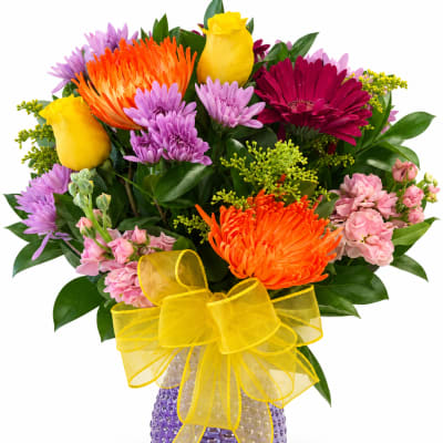Colorful bouquet of mixed flowers in a purple vase with a yellow bow