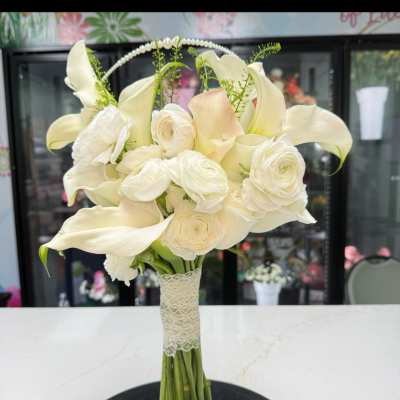 White bridal bouquet with calla lilies, ranunculus, and roses