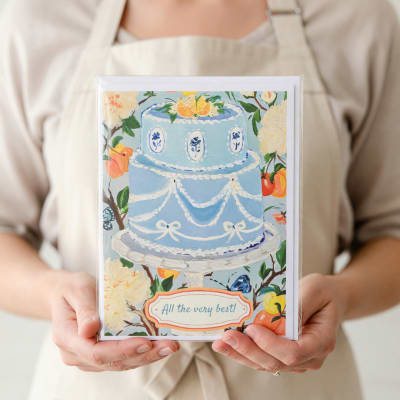 Person holding a greeting card with a blue cake illustration