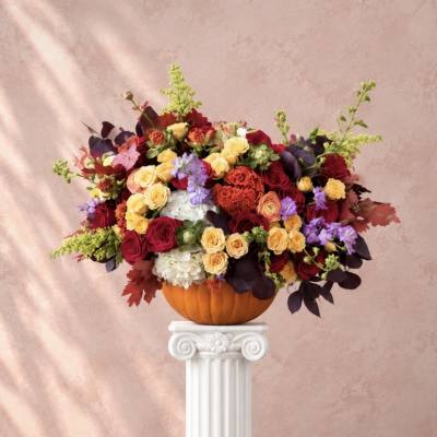 Mixed roses and hydrangeas arranged in a pumpkin vase