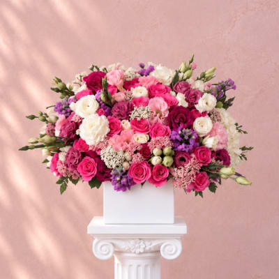 Large pink, white, and purple rose arrangement in a white box